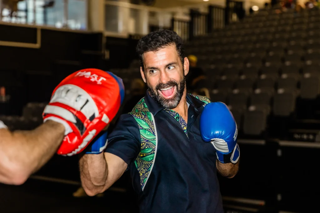 Male individual in boxing class practicing with partner smiling