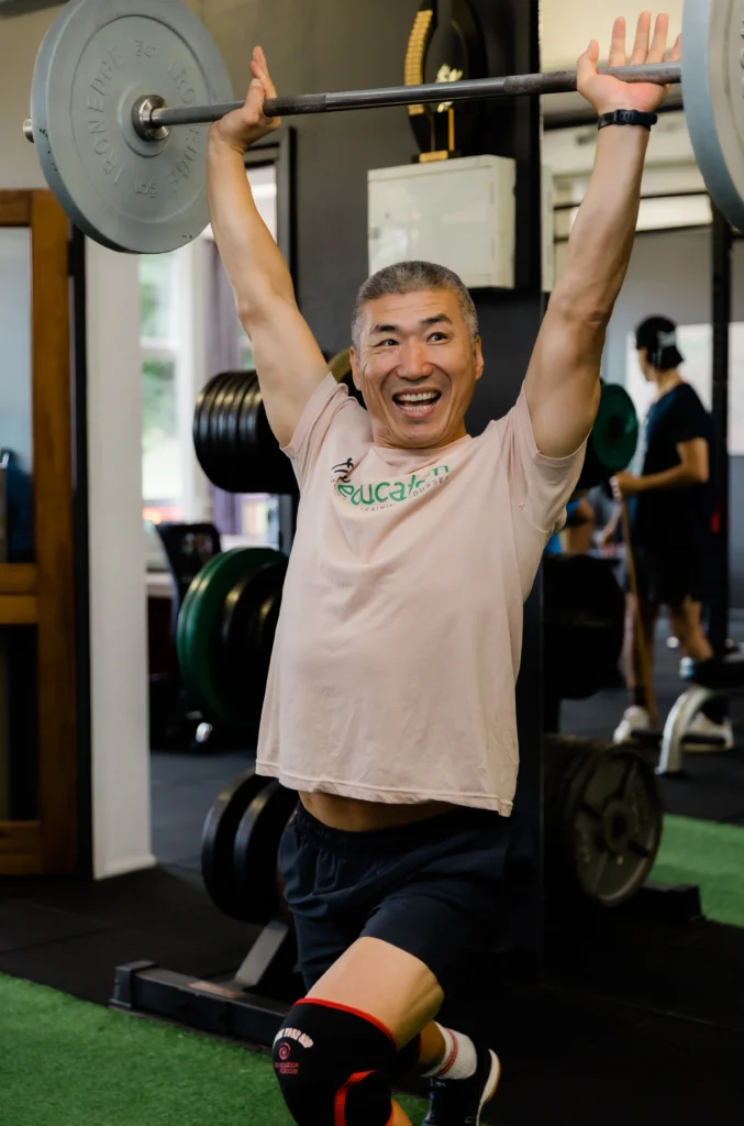 Personal trainer smiling during overhead barbell press