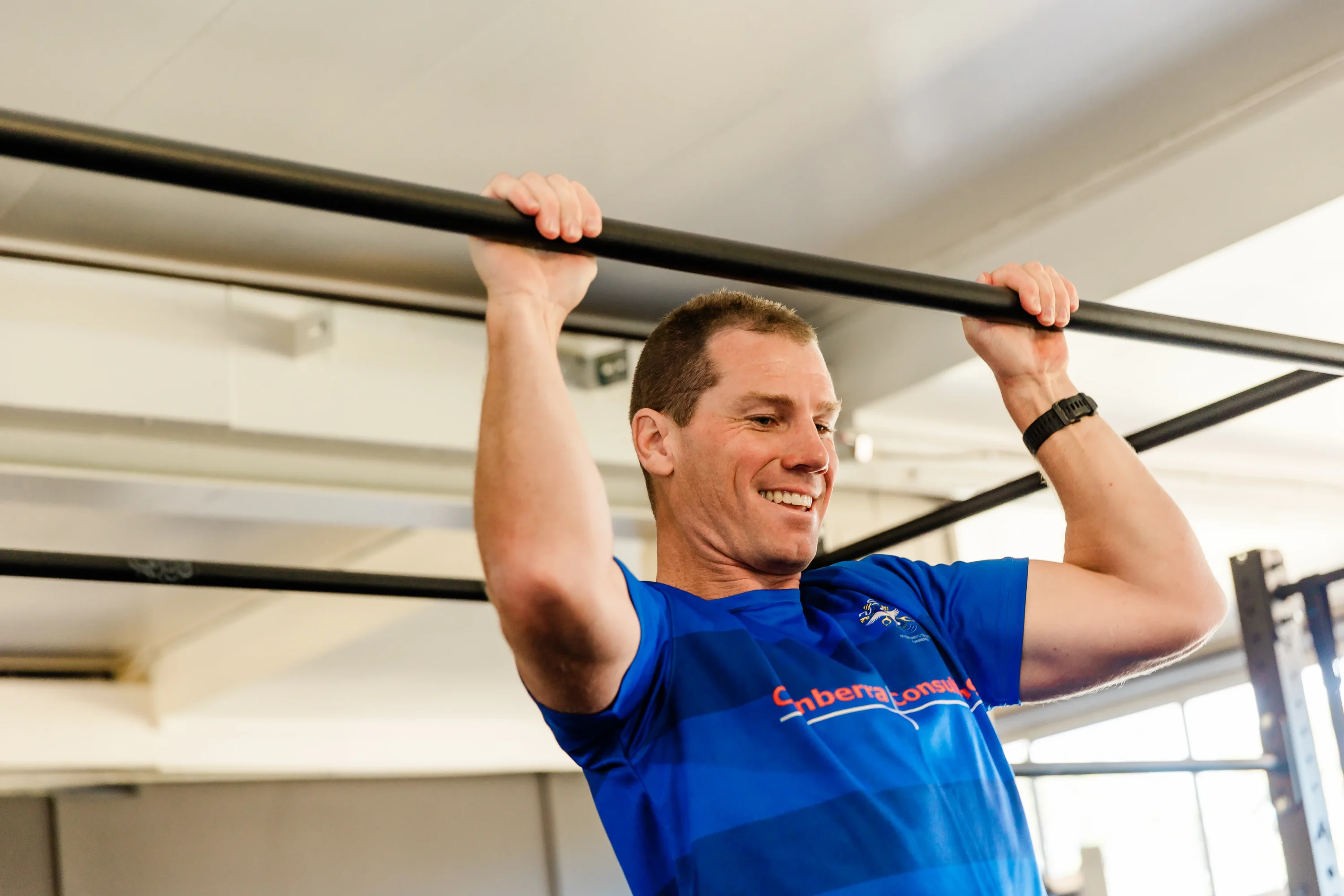Male individual smiling in middle of pull up exercise