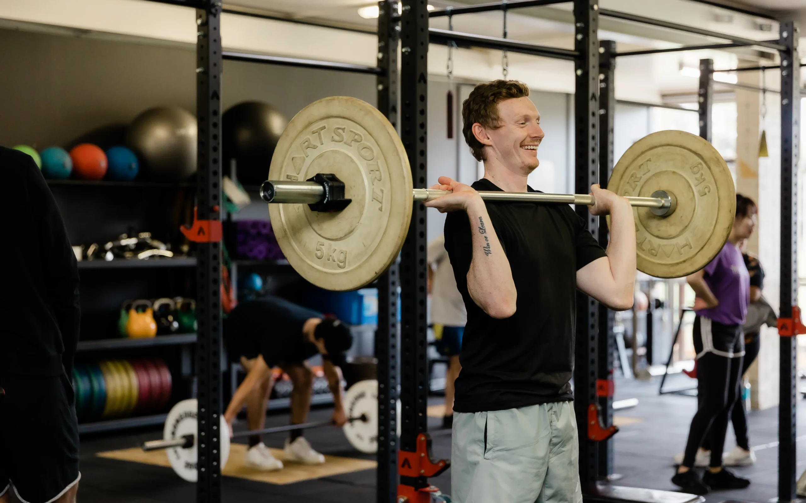 Male client laughing during upper body exercise in gym class