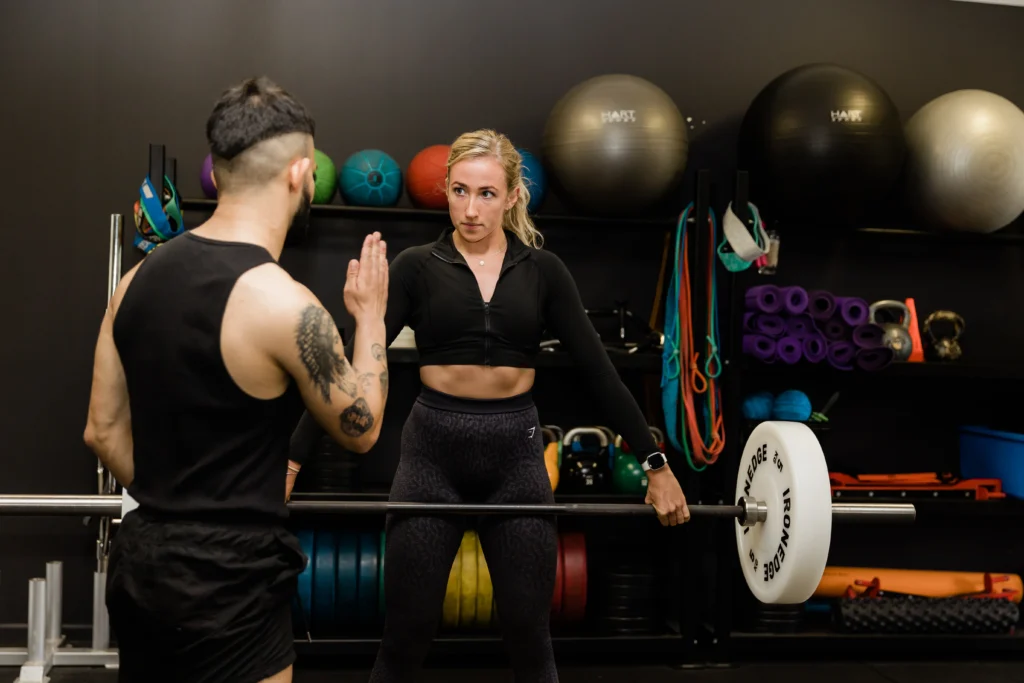 Personal trainer providing guidance to client in gym