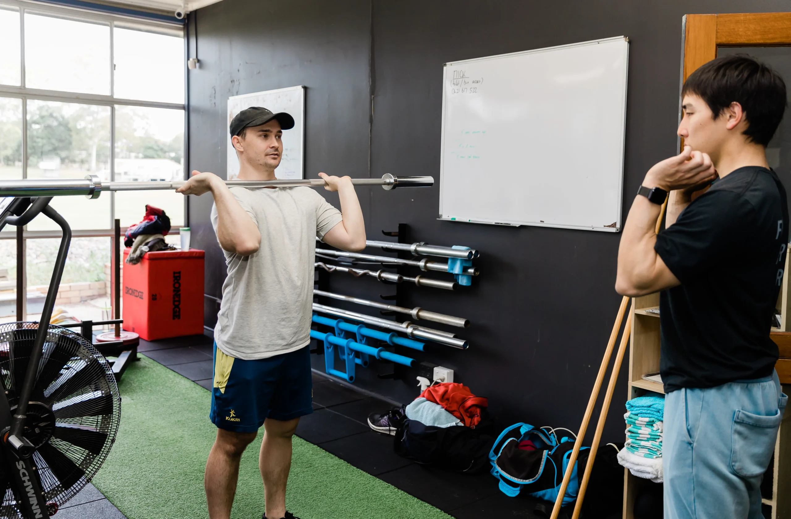 Personal trainer guiding exercise form with client watching