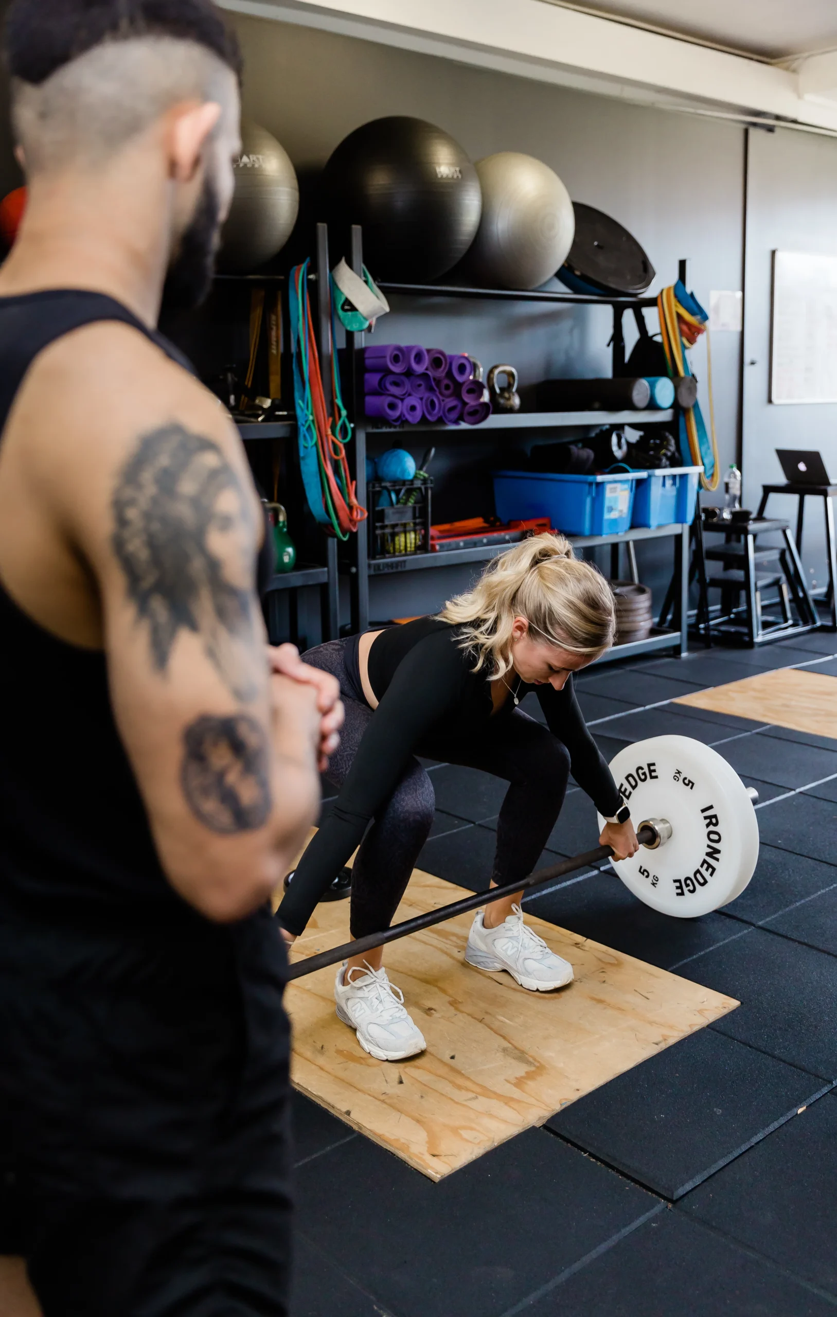 Personal trainer observing client form during deadlift